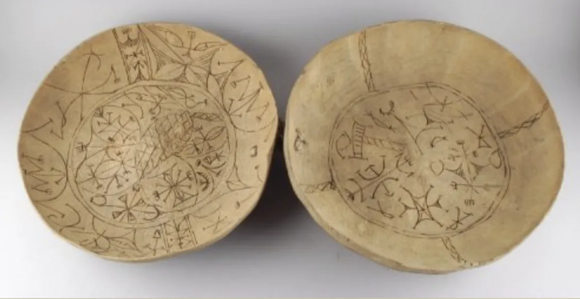 Two pale calabash bowls seen from above, their insides incised with dense Nsibidi signs arranged in circles and bands.